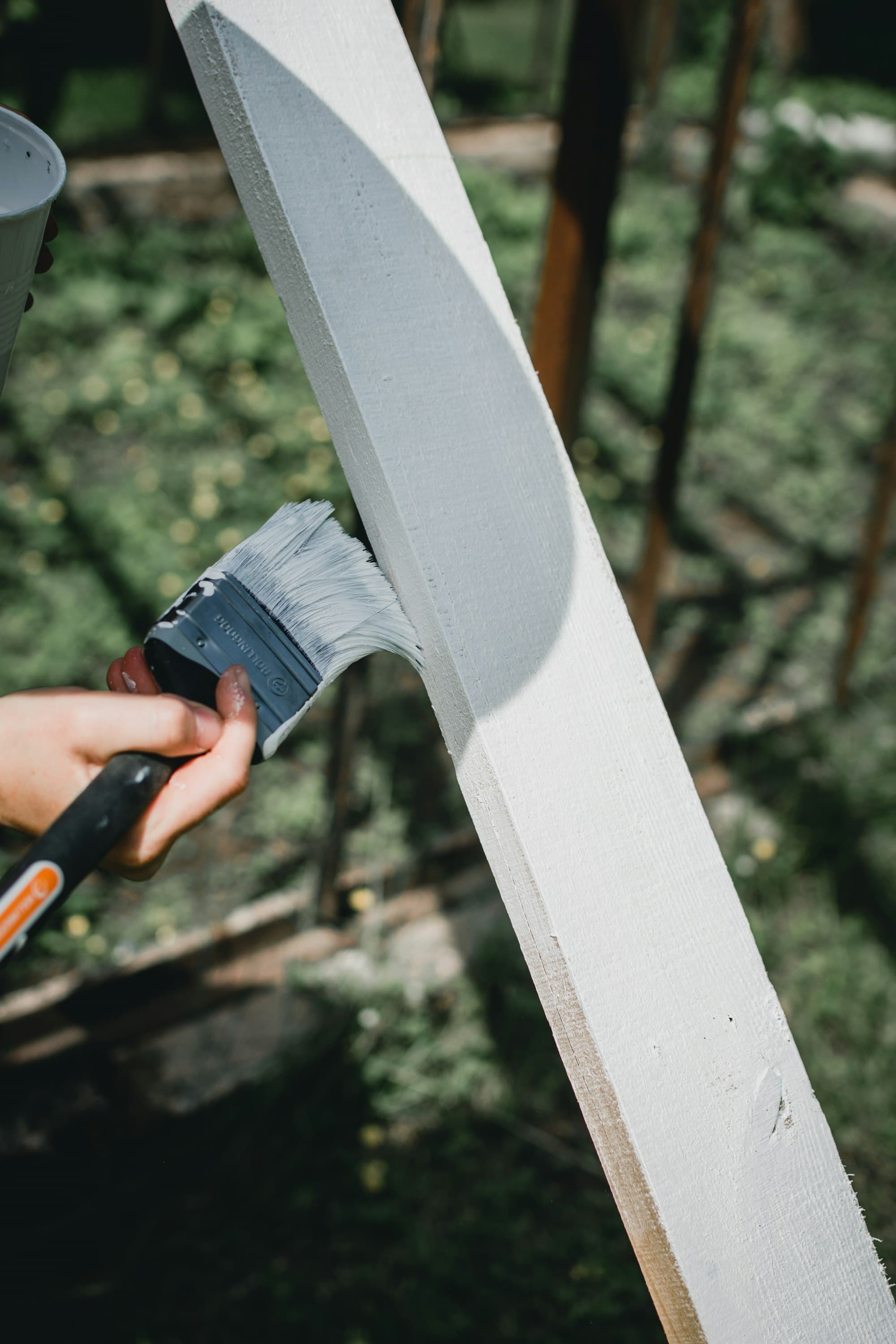 Painter carefully coating white-painted exterior wood plank trim