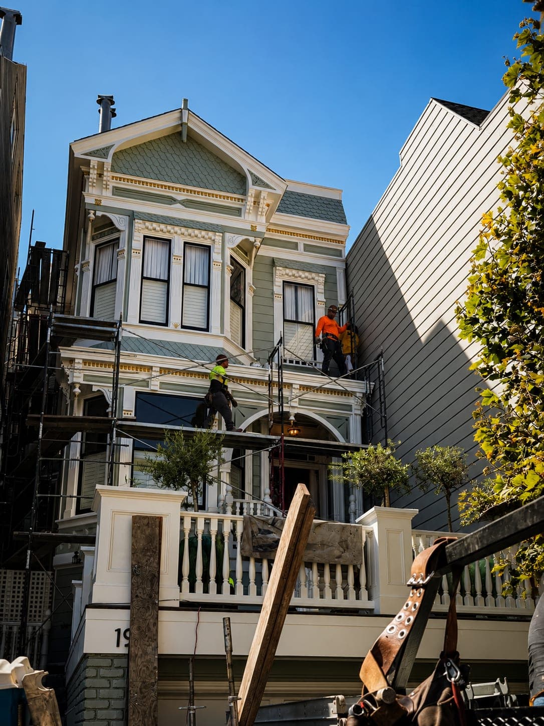 Mid-restoration: RS Professional Painting crew on scaffolding working on the sage-green Italianate Victorian